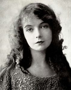 an old black and white photo of a young woman with long hair wearing a dress