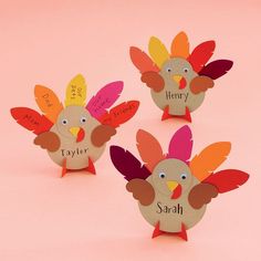 three paper turkeys with name tags on them sitting in front of a pink background