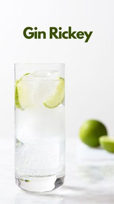 a glass filled with ice and limes on top of a table next to an advertisement for gin rickey