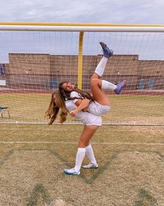 a woman in white shirt and shorts kicking a soccer ball with her leg on the ground