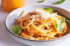 a white bowl filled with pasta and topped with parmesan cheese