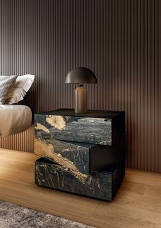 a bed sitting next to a night stand on top of a wooden floor