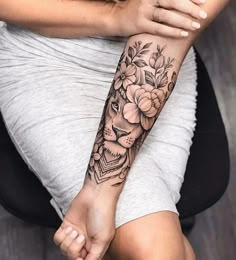 a woman's arm with flowers and a lion tattoo on her left arm,