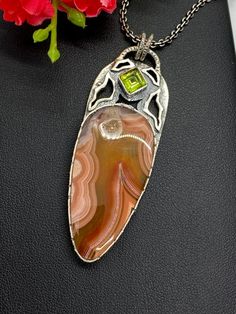 Artisan Laguna Lace Agate pendant comes with 18 inches silver chain  Hand-made Sterling Silver 925.  Stones used: Laguna Lace Agate, Peridot.  Height -2 1/2” (with bail), Width – 15/16”  Height – 62mm, width-23mmUnique Handcrafted One-of a-kind Design Pendant.Each Piece of Jewelry in my Collection is Absolutely One of a Kind!When you start wearing a piece of my jewelry you will fall in love with it more and more each day and feel that good Energy and Love that I pass into it while creating this Artisan Chalcedony Pendant Necklace, Artisan Agate Cabochon Necklace, Artisan Agate Jewelry With Large Pendant, Elegant Agate Pendant Jewelry, Unique Chalcedony Pendant Necklace, Artisan Carved Agate Necklaces, Collectible Agate Pendant Jewelry, Amber Gemstone, Mismatched Earrings