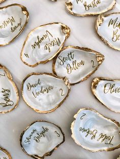 some white and gold oysters with names written on the inside of them, sitting on a table