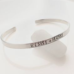 "Resist Bracelet - sterling silver cuff bracelet - political jewelry One 1/8\" x 6\" sterling silver cuff bracelet made from 18 gauge sterling sheet. It is hammered, and then stamped with the words Resist and Persist As with all hand stamped jewelry, each piece is made just for you, so there may be slight differences. This is not to be seen as a defect, but as part of the character of the piece. Thank you for your understanding. Production time may vary as each one is made to order. Please see m Minimalist Hand Stamped Sterling Silver Bracelets, Adjustable Hand Stamped Sterling Silver Bracelet, Hand Stamped Sterling Silver Cuff Bangle, Adjustable Stamped Minimalist Cuff Bracelet, Minimalist Stamped Adjustable Cuff Bracelet, Hand Stamped Sterling Silver Cuff Bracelet, Minimalist Silver Cuff Bracelet With Hand Stamped Details, Sterling Silver Cuff Bracelet Hand Stamped, Adjustable Sterling Silver Stamped Cuff Bracelet