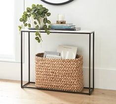 a small table with a basket underneath it and a clock on the wall behind it