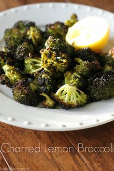 a white plate topped with broccoli and lemon wedges