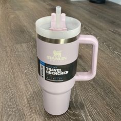 a pink travel mug sitting on top of a wooden table