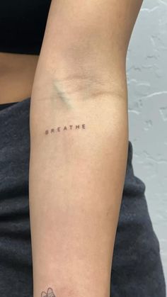 a woman's arm with the word breathe tattooed on her left arm, and a clover