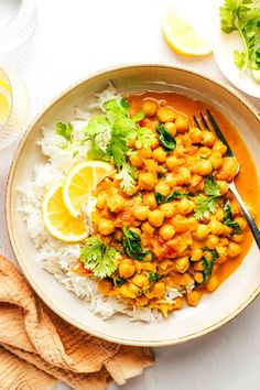 a bowl filled with rice and chickpeas on top of a table next to lemon wedges