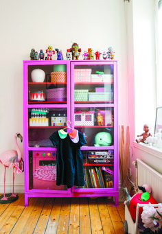 a pink bookcase filled with lots of toys