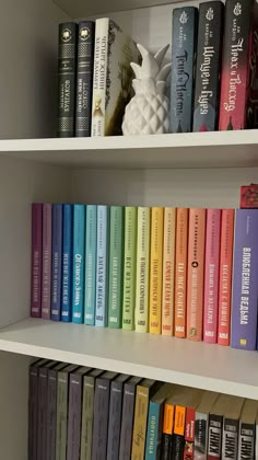 a row of books sitting on top of a white book shelf next to each other