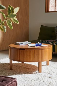 a wooden coffee table sitting on top of a white rug next to a potted plant