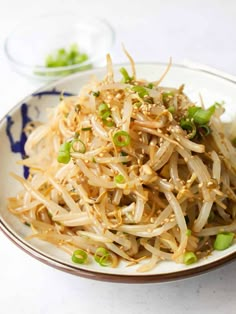 a white plate topped with noodles and green onions