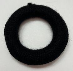 a black knitted ring sitting on top of a white table