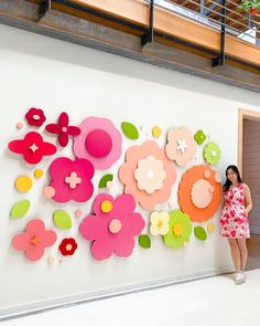 a woman standing in front of a wall with paper flowers on it and an open door