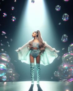 a woman standing on top of a stage in front of bubbles