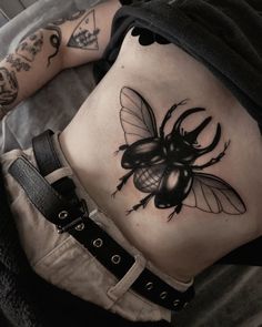 a black and white photo of a woman's stomach with a bee tattoo on it