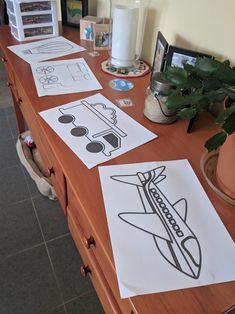 some paper cut outs on a table with plants and pictures in the background for kids to draw