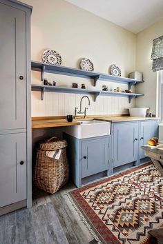 a kitchen with blue cabinets and white walls, an area rug and wooden flooring