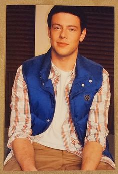 a man sitting down wearing a blue vest