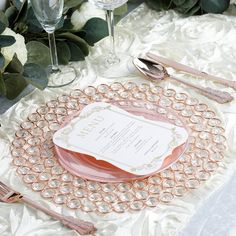 the table is set with pink and white plates, silverware, and napkins