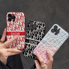 two people holding up cell phones with mickey mouse cases on them, one is red and the other is black