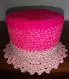 a pink and white crocheted hat sitting on top of a wooden table