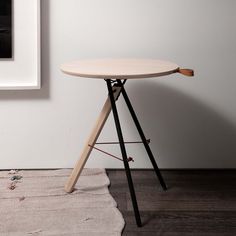 a wooden table sitting on top of a hard wood floor next to a white wall