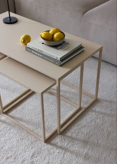 two tables with books and lemons on them in front of a white couch,