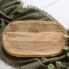 a wooden cutting board sitting on top of a green cloth next to some greenery