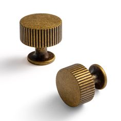 two brass knobs on white background one has a striped design and the other has a black stripe pattern