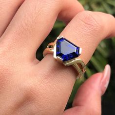 a close up of a person's hand holding a ring with a blue stone