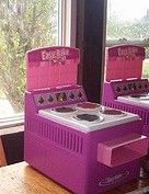 three pink toy stoves sitting on top of a wooden table next to a window