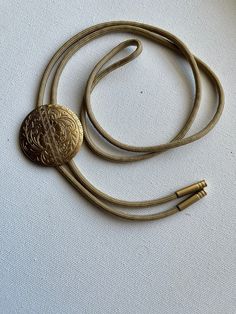 Brass floral medallion bolo tie necklace on light gold colored nylon cord. Gold Bolo Tie, Elegant Adjustable Medallion Necklace For Gift, Elegant Adjustable Round Medallion Necklace, Elegant Round Medallion Necklace, Gold Adjustable Cord Bolo Ties For Gift, Adjustable Gold Bolo Tie As Gift, Gold Bolo Ties With Adjustable Cord As Gift, Gold Bolo Ties With Adjustable Cord For Gifts, Elegant Adjustable Bronze Necklace