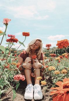 a woman sitting on the ground surrounded by flowers