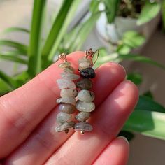 a person holding some kind of bead in their hand with plants in the background