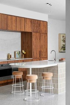 three stools sit at the center of a kitchen island in front of an oven