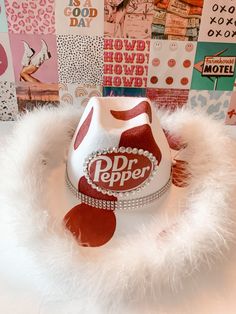 a red and white hat sitting on top of a pile of paper with pictures behind it