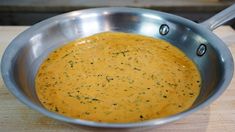 a metal pan filled with yellow sauce on top of a wooden table