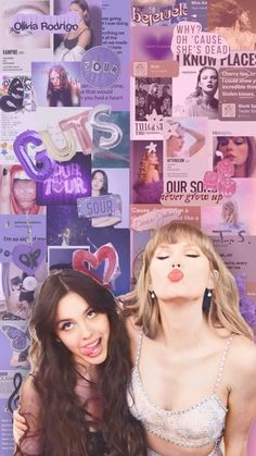 two beautiful women standing next to each other in front of a wall covered with posters