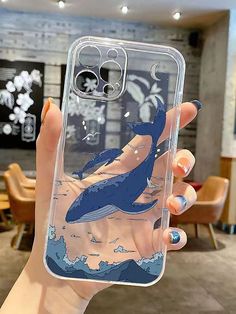 a woman holding up a phone case with a whale on it