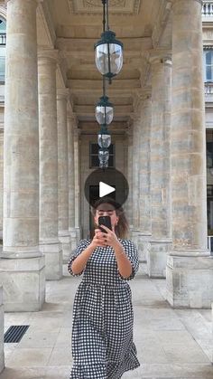 a woman taking a selfie in front of an old building with columns and lights