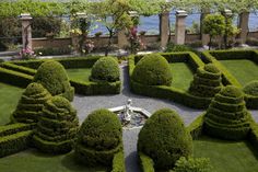 a garden with hedges and water in the background