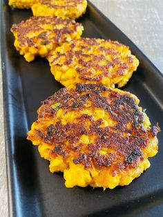 three crab cakes sitting on top of a black plate