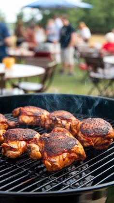 some food is being grilled on a bbq with people in the back ground