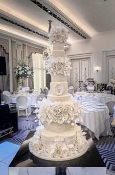 a large white wedding cake sitting on top of a table in a room filled with tables and chairs