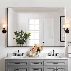 a bathroom vanity with two sinks and a large mirror above it, along with flowers