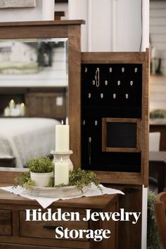 the hidden jewelry storage cabinet is open and has candles on it, next to a candle holder